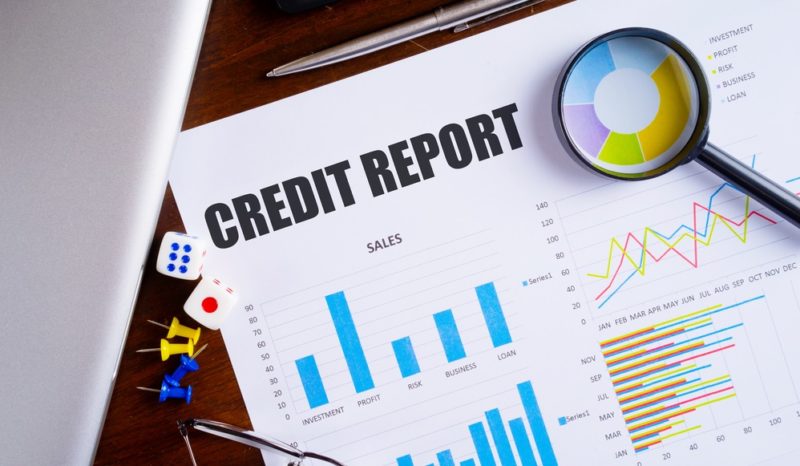 credit report text on paper sheet with magnifying glass on chart